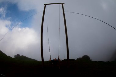 Gün batımında güzel gökyüzü ile plajda büyük salıncakta sallanan kimliği belirsiz adam. Büyük salıncak, turistlerin oynamaları için sağlanan palmiye ağacından sarkıyor..