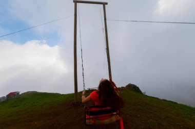 Gün batımında güzel gökyüzü ile plajda büyük salıncakta sallanan kimliği belirsiz adam. Büyük salıncak, turistlerin oynamaları için sağlanan palmiye ağacından sarkıyor..