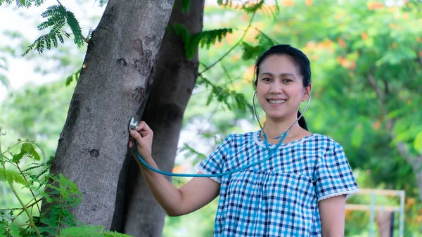 Una hermosa chica usando estetoscopio para el chequeo de salud del árbol — Foto de Stock