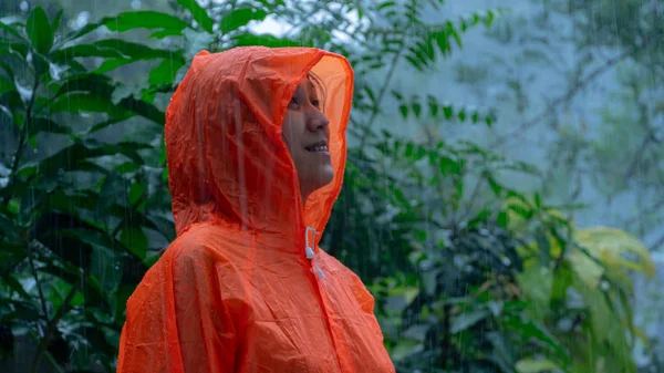 Woman wearing orange raincoat out in the rain