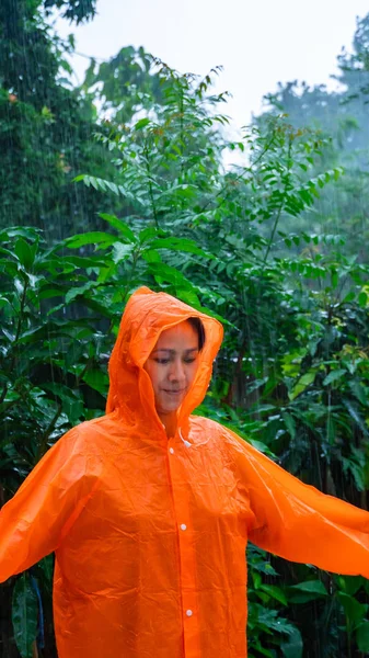 Mujer con impermeable naranja en la lluvia —  Fotos de Stock