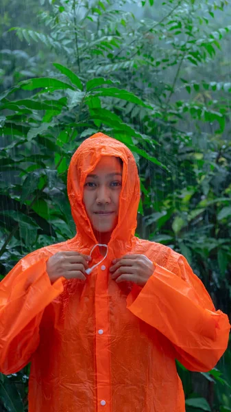 Donna che indossa l'impermeabile arancione sotto la pioggia — Foto Stock