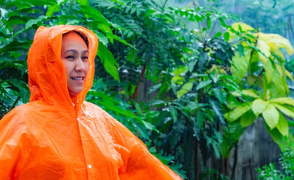 Mujer con impermeable naranja en la lluvia —  Fotos de Stock