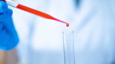 Laboratuvarda araştırmacılar virüsler için test tüpünde kan damlama