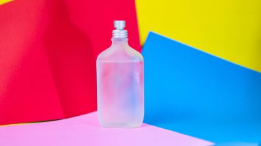 Kağıt renkli arka plan üzerinde bir parfüm şişesi