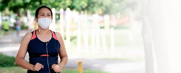 Portrait of Asia woman wearing mask jogging in the park