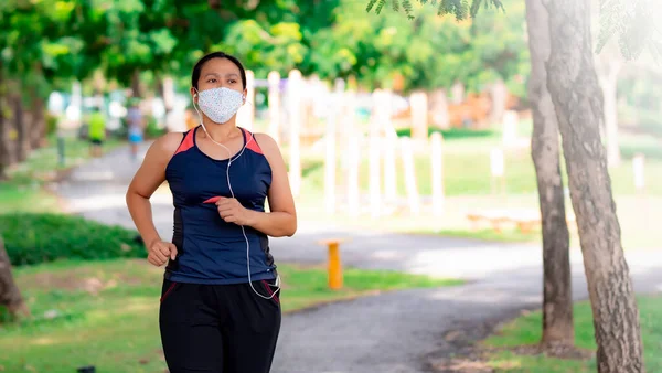 Portrait of Asia woman wearing mask jogging in the park