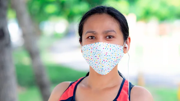 Portrait of Asia woman wearing mask jogging in the park