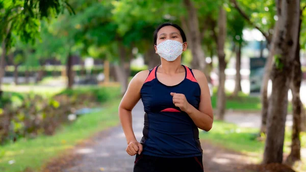 Portrait of Asia woman wearing mask jogging in the park