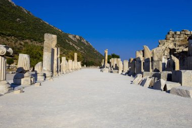 Perspektif görünümü Efes Antik şehir mavi gökyüzü ve dağlar karşı sütunlarla Caddesi'nin.