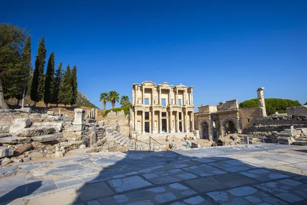 Kare Kütüphane, antik kalıntıları ile ilgilenen turist yakınındaki antik Roma kütüphane mavi gökyüzü ve palmiye ağaçları karşı cephe görünümü.