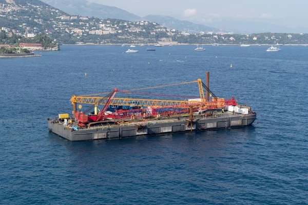 A construction crane barge begins land reclamation work off the coast of Monaco