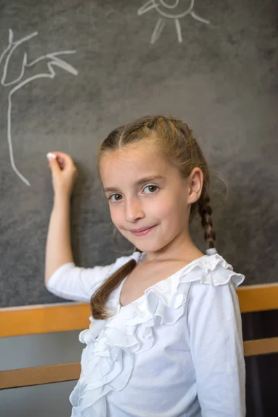 Elementary student drawing on blackboard — Stock Photo, Image