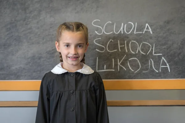 Δημοτικό σχολείο κορίτσι μαθήτρια με στολή στον πίνακα — Φωτογραφία Αρχείου
