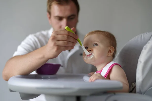 Vader Voedt Dochtertje Met Lepel Kinderstoel — Stockfoto