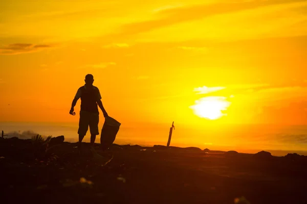 An Indonesian Man collecting garbages nearby the ocean of the Bali island, Indonesia. Bali is known as the beautiful ocean view with with exotic culture of Indonesia.