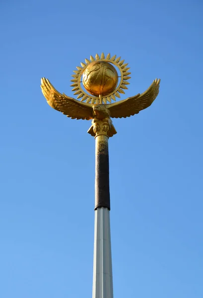 Symbols of Kazakhstan: Golden eagle and golden sun in a clean blue sky.