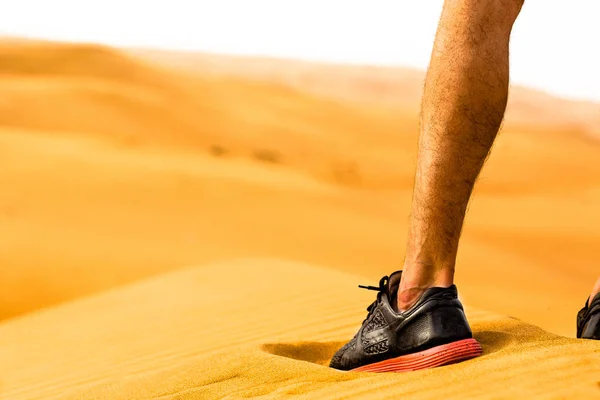 A man getting ready to run outside in nature. Closeup of  a runner's feet on the dessert sand.