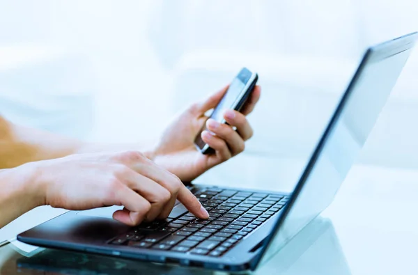 Tipik üstünde bilgisayar ve cep telefonu arayan iş kişi yakın çekim.