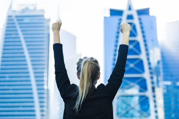 Business success - Celebrating businesswoman overlooking the city center high-rises