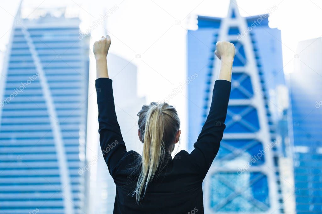 Business success - Celebrating businesswoman overlooking the city center high-rises