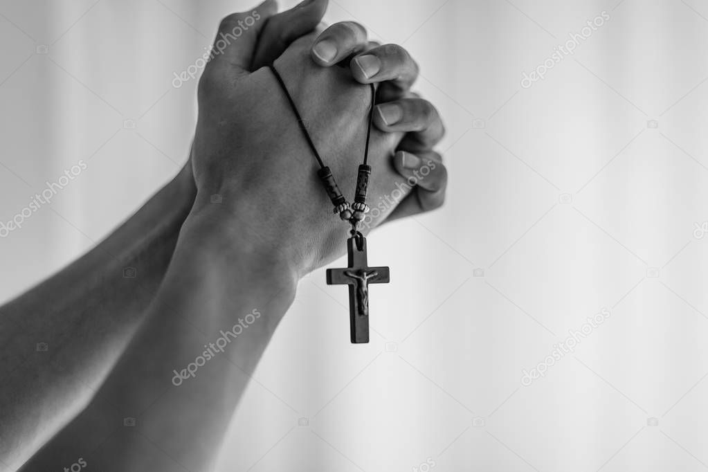 Praying hands holding a rosary.
