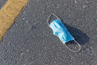 Tek kullanımlık tıbbi maske, yolda bırakılmış. Covid-19 salgını sırasında çevre kirliliği ve atıkları.