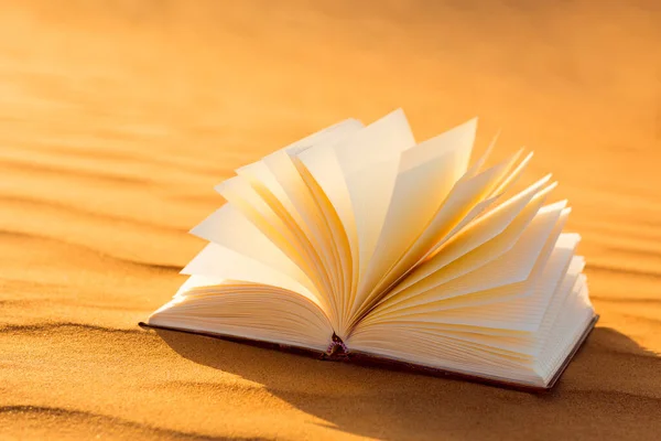 Gün batımında Arap altın çölünde uzanan sayfaların döndüğü boş bir kitap. Edebiyat ve kültür.