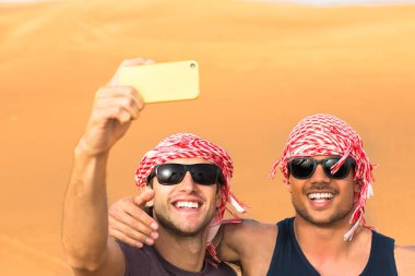 Turizm ve Arkadaşlık - Mutlu yetişkin erkek arkadaşlar Arap çöl kumulları safarisinde selfie çekiyorlar..