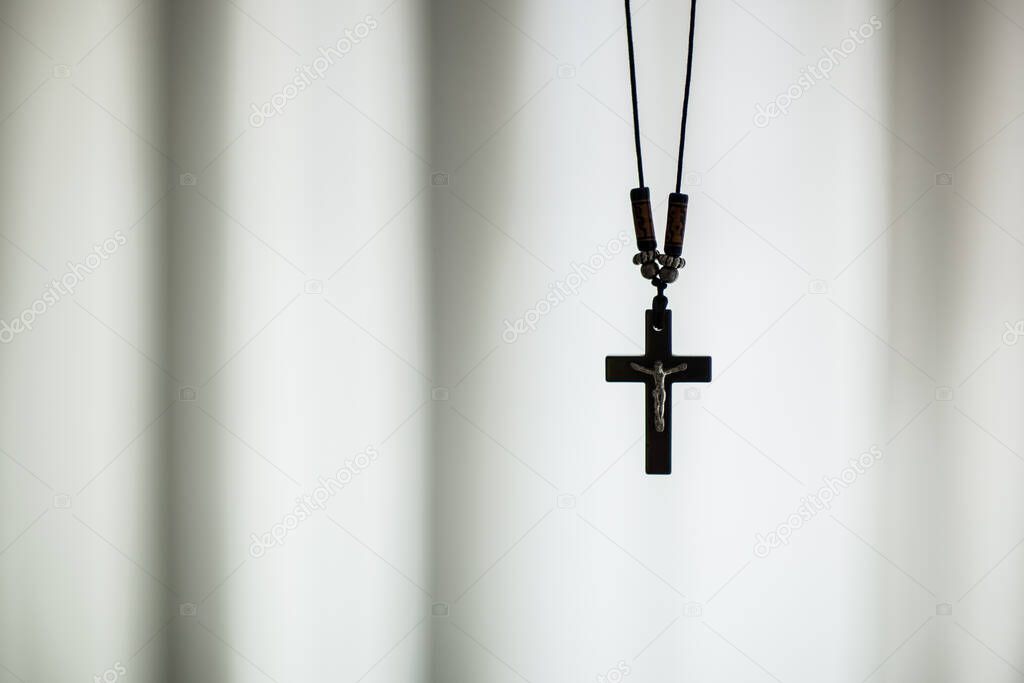 Christian pendant with a crucifix cross hanging up. Black and white closeup.