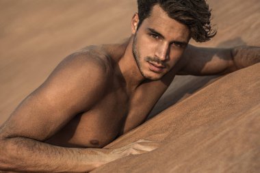 Çölde yatan seksi, yakışıklı, üstsüz erkek model. Güzel portre..