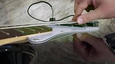 Müzisyen bas gitar çalıyor. Ateş--dan farklı açı yapılır. Büyük eller ve dizeleri
