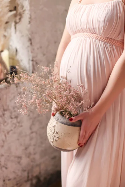 Pembe çiçekli vazo içinde hamile kadın tutar. Gebelik, hamile, hazırlık ve beklenti kavramı. Yakın çekim, kopya alanı, kapalı. Gebeliğin güzel ihale ruh fotoğraf.