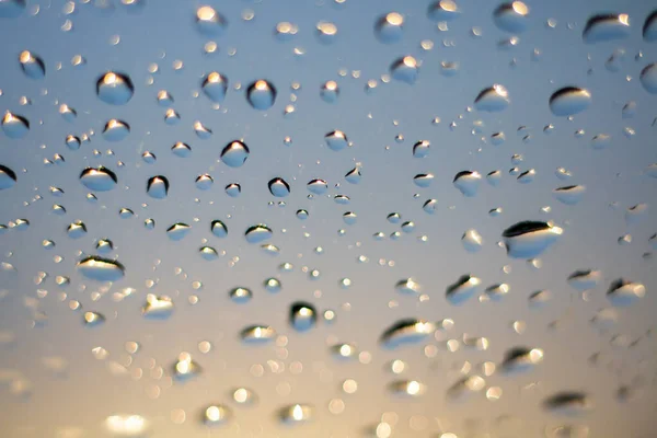 真ん中に黄色の太陽の光と車の窓の上に雨が降り 非常に上に青い色の空 太陽光線の屈折 水滴を通過する光 青フレッシュビュー — ストック写真