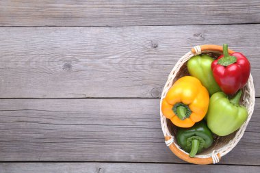 Taze biber gri arka plan üzerinde bir sepet içinde. Kırmızı, yeşil, sarı masada kırmızı biber.