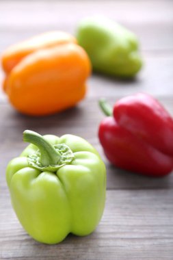 Ahşap zemin üzerine yeşil, sarı ve kırmızı dolmalık biber