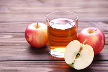 Olgun kırmızı elma suyu üzerinde kahverengi ahşap bir masa ile