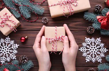 Hediye kutusu kahverengi ahşap masa üzerinde tutan eller. Noel kompozisyon