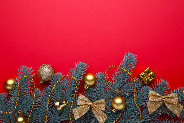 Рождественское украшение. Ветка ели с золотыми шариками, маленькими подарками и луками на красном фоне. Новогодняя композиция
