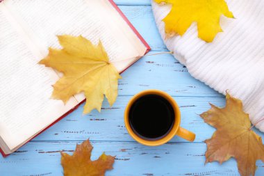 Sonbahar yaprakları ve mavi ahşap zemin üzerine eski kitap ile kahve