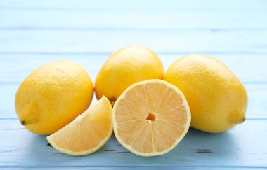 Limon ve yarım limon mavi zemin üzerine. Taze tropikal meyve.