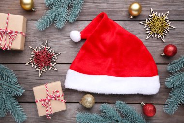 Noel Baba kırmızı şapka ve gri arka plan üzerinde hediyeler. Köknar ağacı dalı topları, gri bir arka plan üzerinde yay ile