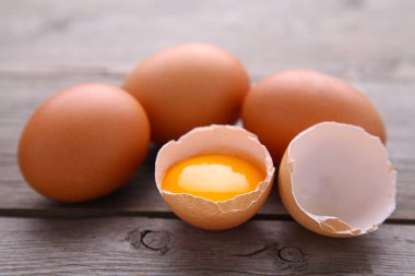 Tavuk yumurtası ve gri bir arka planda sarısı yarısıyla. Gri bir ahşap masa üzerinde yumurta