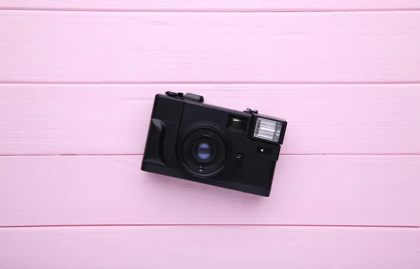 Vintage camera on pink wooden background. Old photo camera on wooden background