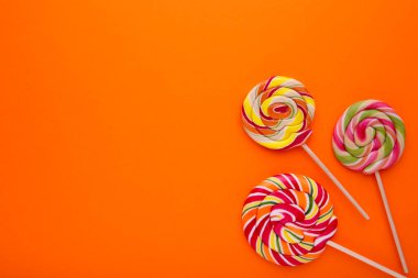 Turuncu arka plan üzerinde renkli lolipop. Stüdyo vurdu