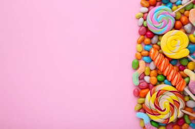 Renkli lolipop ve farklı renkli şeker pembe üzerinde yuvarlak