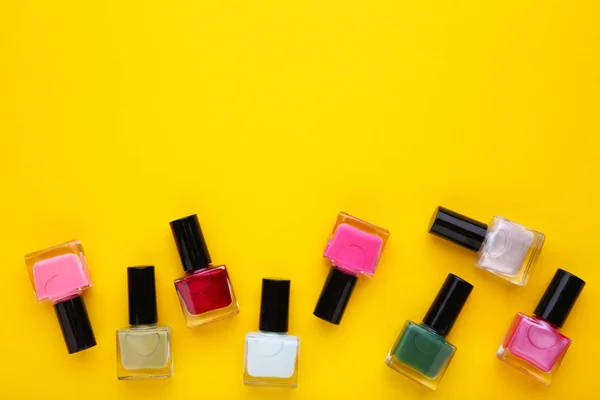 Group of bright nail polishes on yellow background