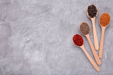 Gri zemin üzerine tahta kaşıklar üzerinde baharat karışımı.