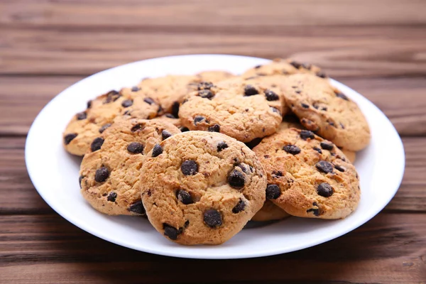 茶色の木製テーブルの上皿にチョコレート チップ クッキー — ストック写真