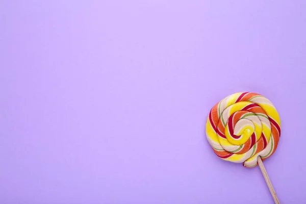 Pirulito colorido no fundo roxo, conceito de doces doces — Fotografia de Stock